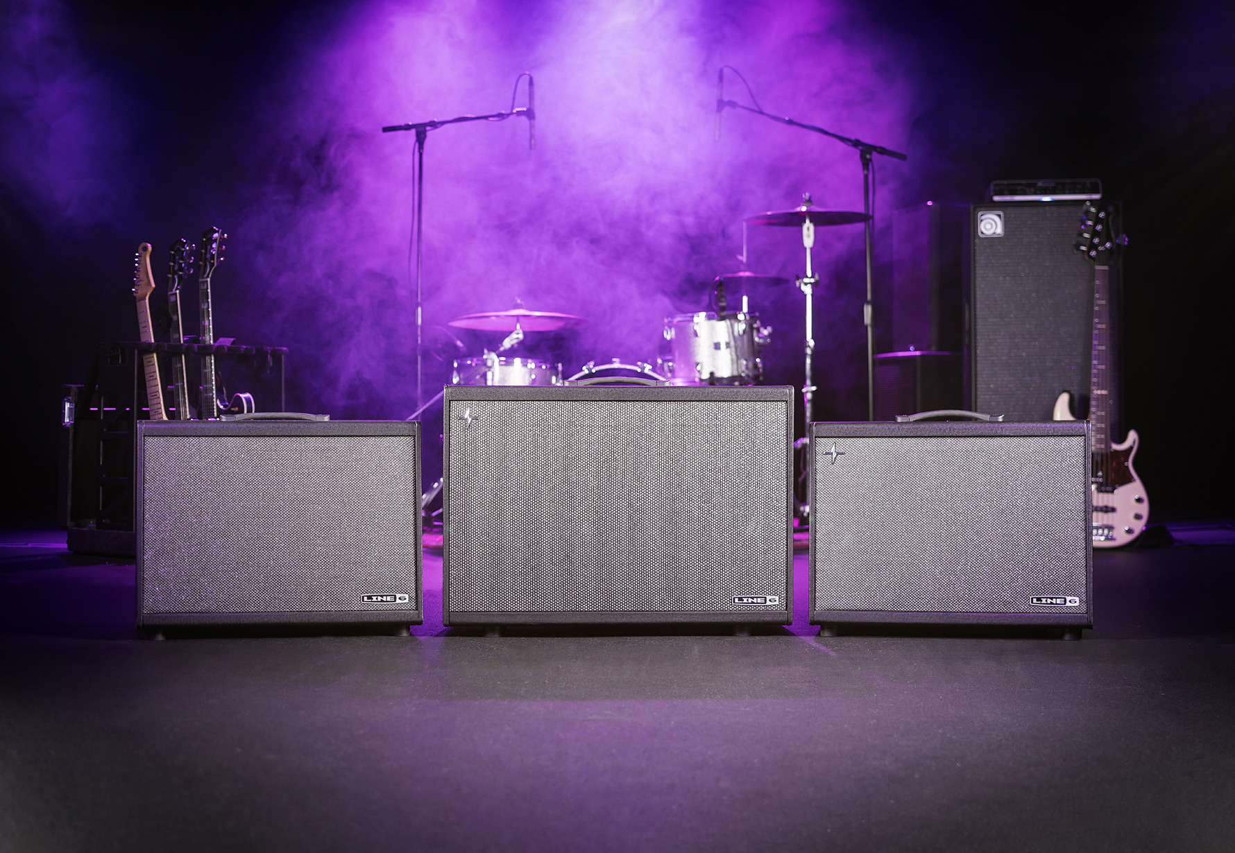 Powercab 112, Powercab 212 Plus, and Powercab 112 plus displayed on stage with guitars, drums and bass and purple lit haze.